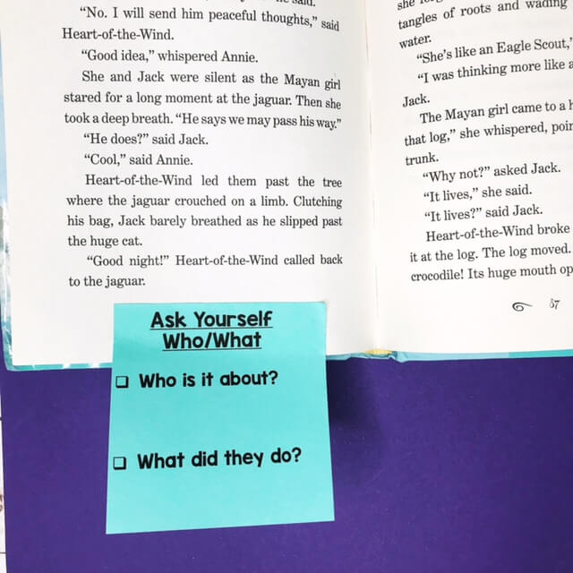 A book is open with a blue sticky note at the bottem. The sticky note says Ask Yourself Who/What. Who is it about? What did they do?